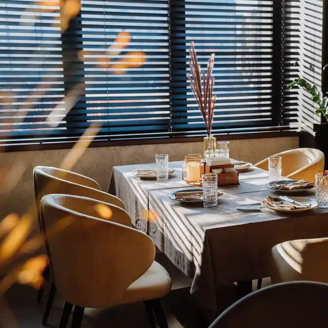 Wnętrze restauracji w Gdańsku z przyciemnionym światłem przez czarne, pochylone lamele żaluzji drewnianych