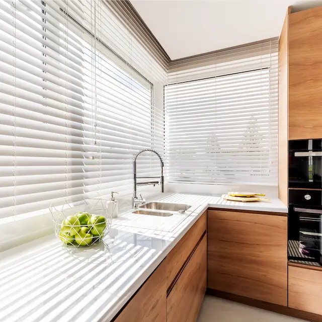 Białe żaluzje drewniane zamontowane w kuchennym oknie w Tczewie