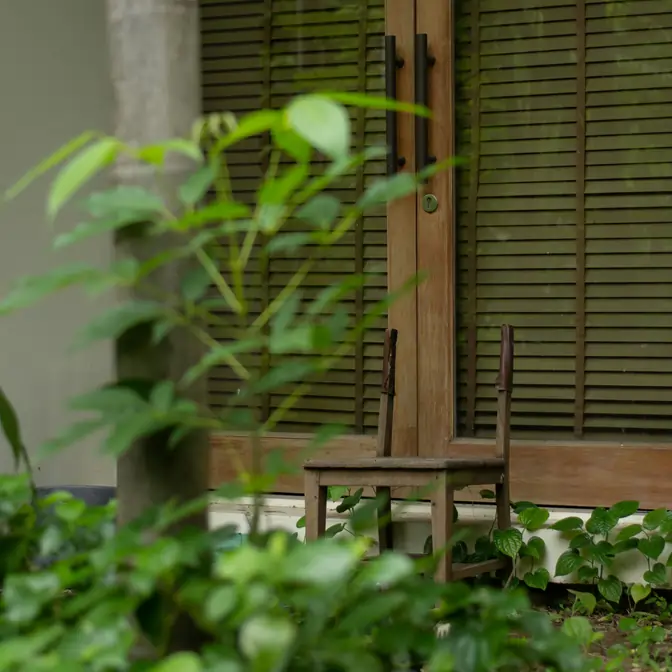 Widok z ogrodu na drzwi tarasowe z beżowymi drewnianymi żaluzjami w Wejherowie