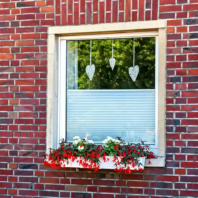 Widok z zewnątrz budynku na okna z roletami plisowanymi w Redzie