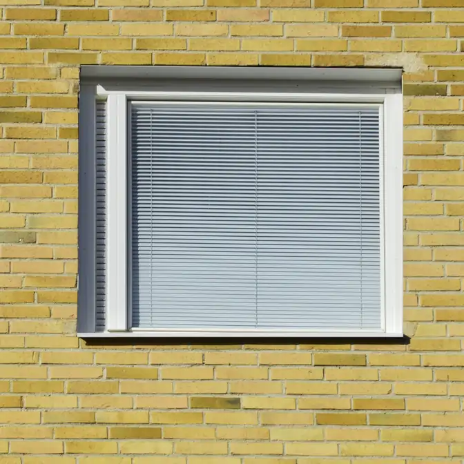 Widok z zewnętrz na okno budynku z zasłoniętą żaluzją aluminiową w Rumii